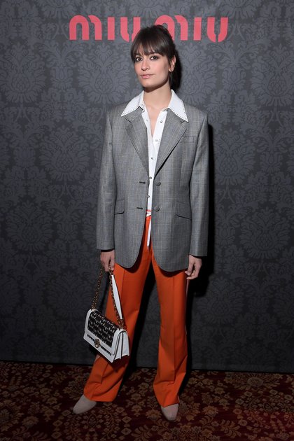 Au défilé Miu Miu, Clara Luciani joue sur les contrastes et les volumes avec une veste de costard oversize et un pantalon à pinces orange.